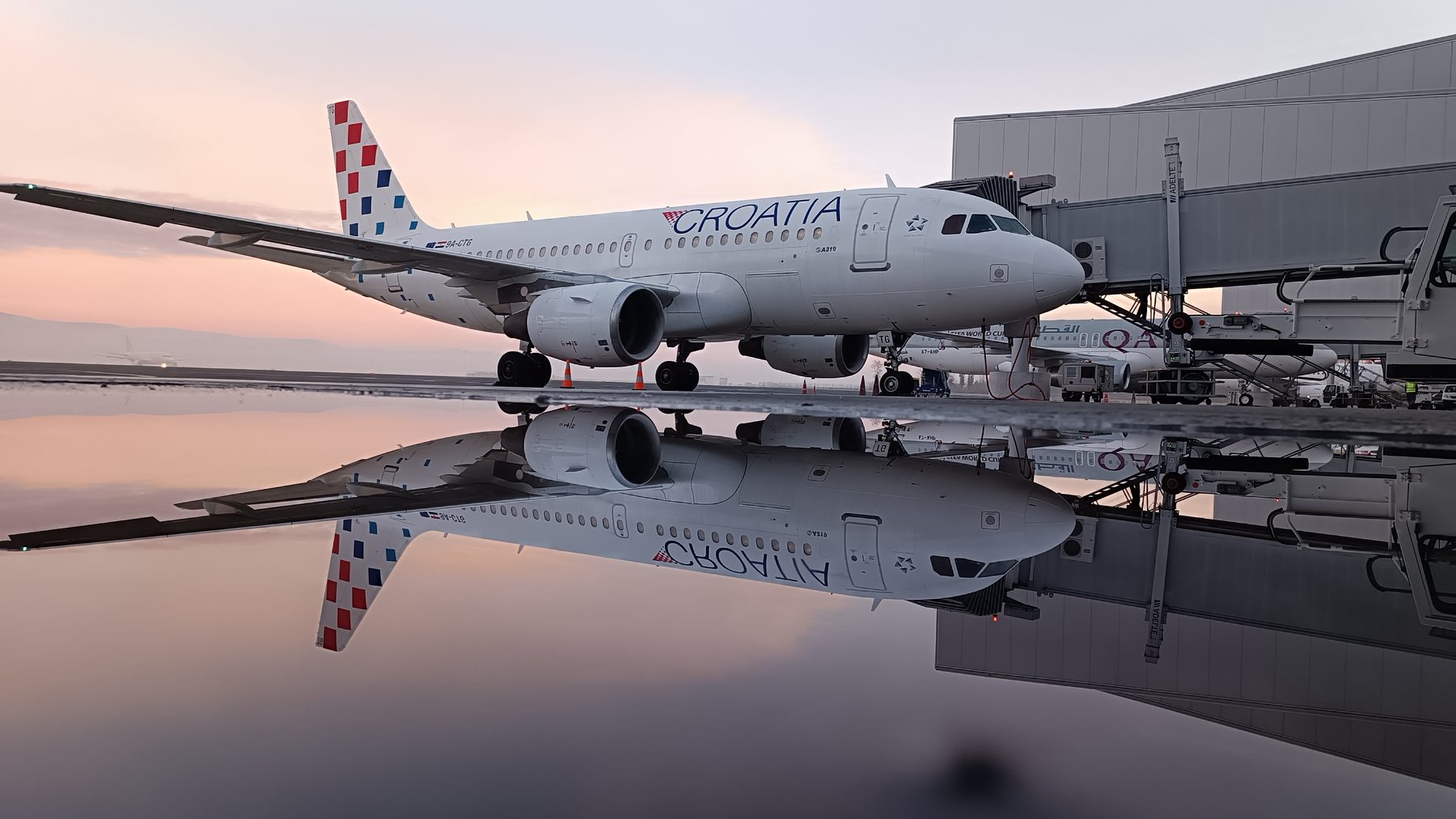 Croatia Airlines A319 mirrored on wet apron at dawn, Zagreb